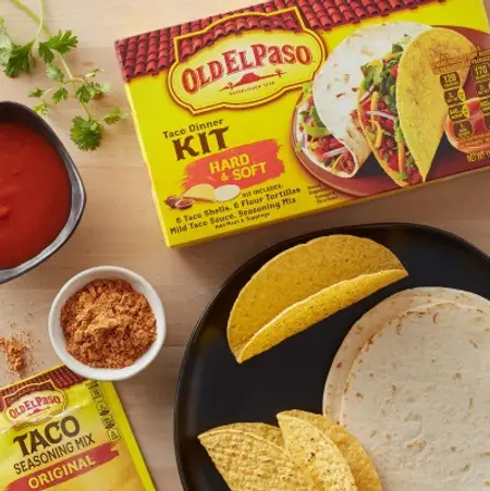 A table with Old El Paso Dinner Kits, tortillas, taco shells, and refried beans 